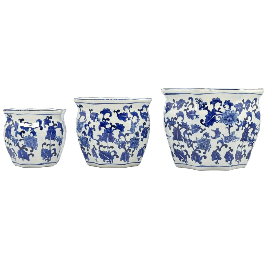 Set of three blue and white ceramic Chinoiserie planter pots with floral patterns and fluted edges.