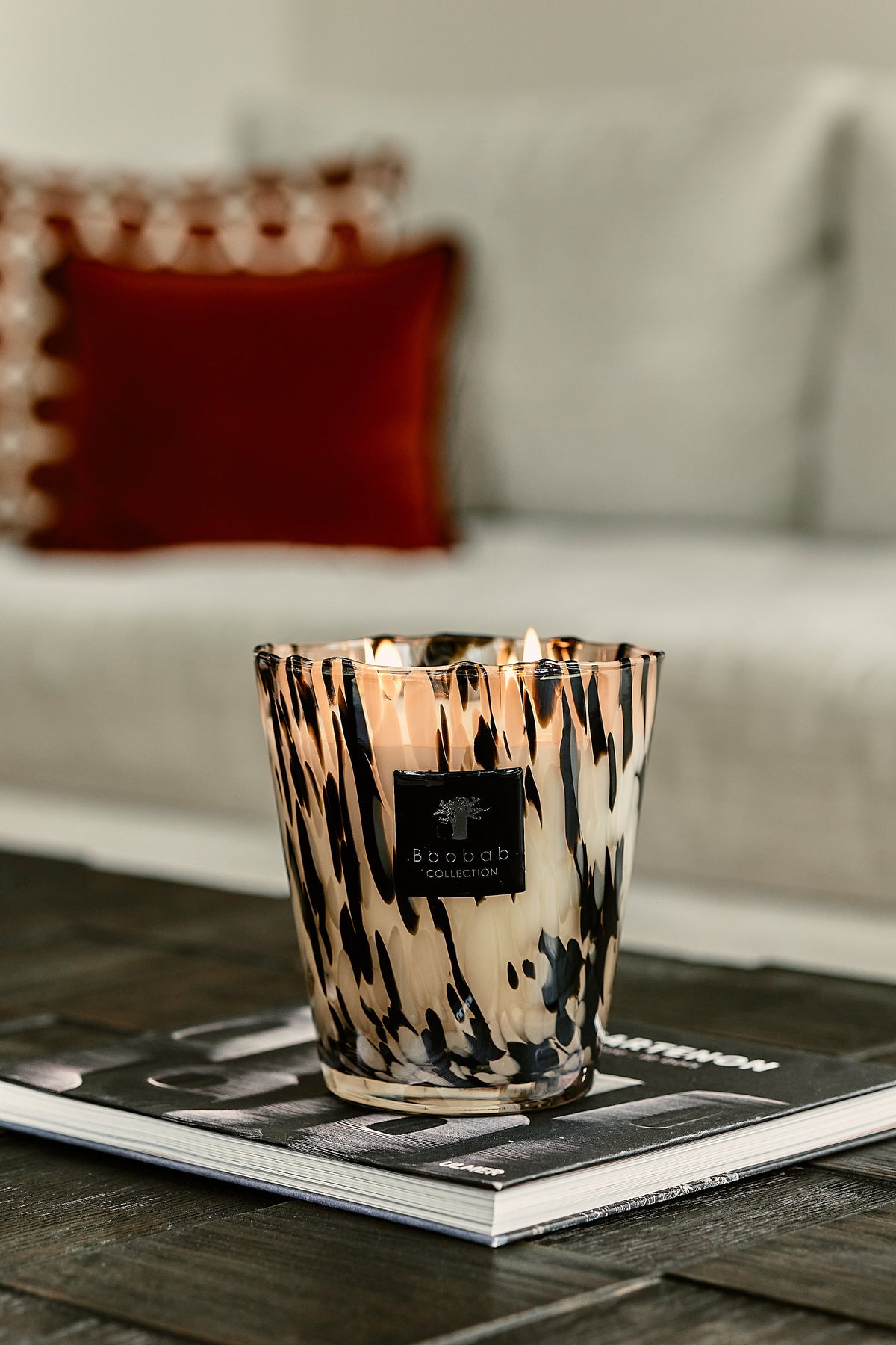 Baobab Collection Black Pearls candle with black and white glass vessel on a coffee table book.