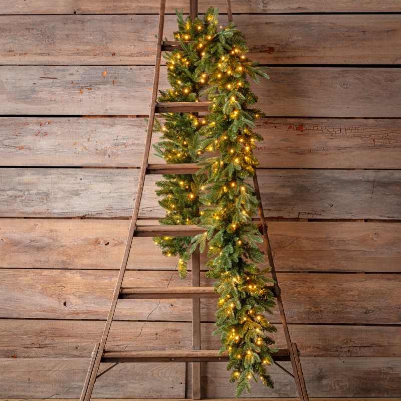 Douglas Fir 9-foot pre-lit garland with warm white lights draped over a rustic wooden ladder.