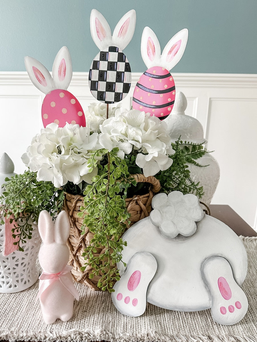 Bunny bottom decoration with pink feet and tail, surrounded by Easter eggs and flowers.