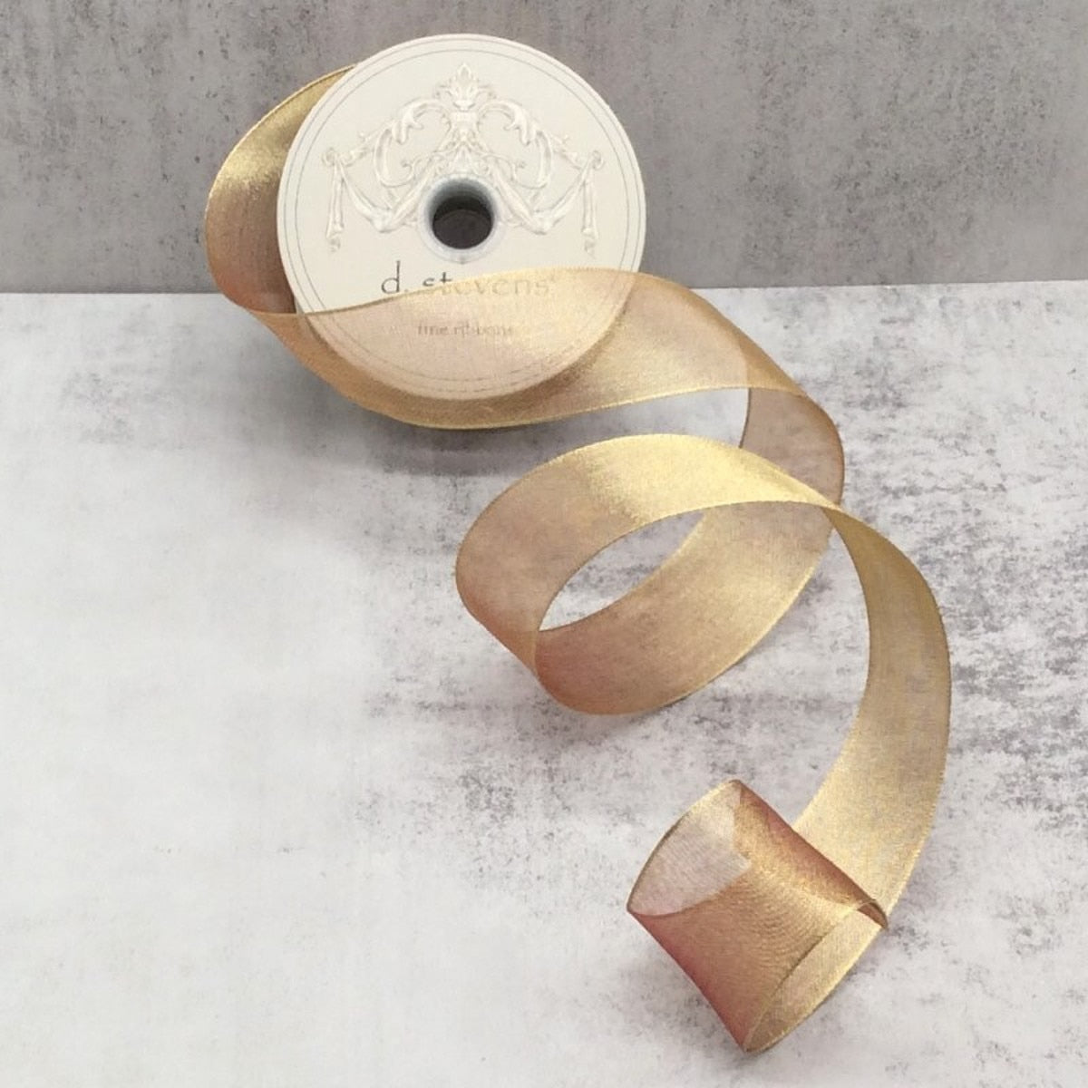 A roll of antique gold metallic mesh fabric measuring 1.5 inches wide by 25 yards long.