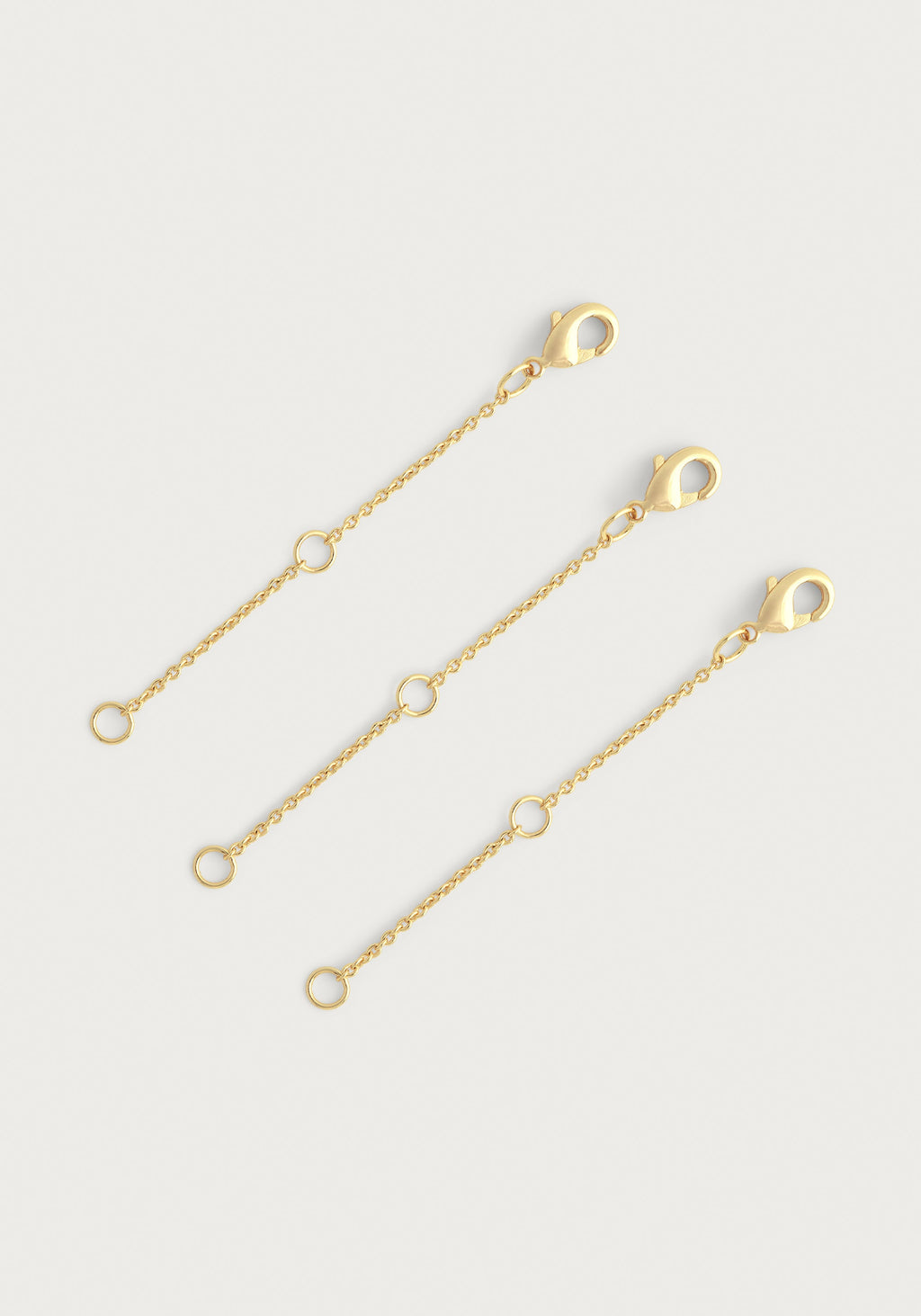 Set of three gold-tone chain extenders with lobster clasps and multiple jump rings.