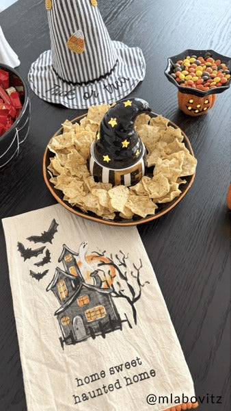 Light-up witch hat chip and dip bowl set surrounded by tortilla chips on a Halloween table.