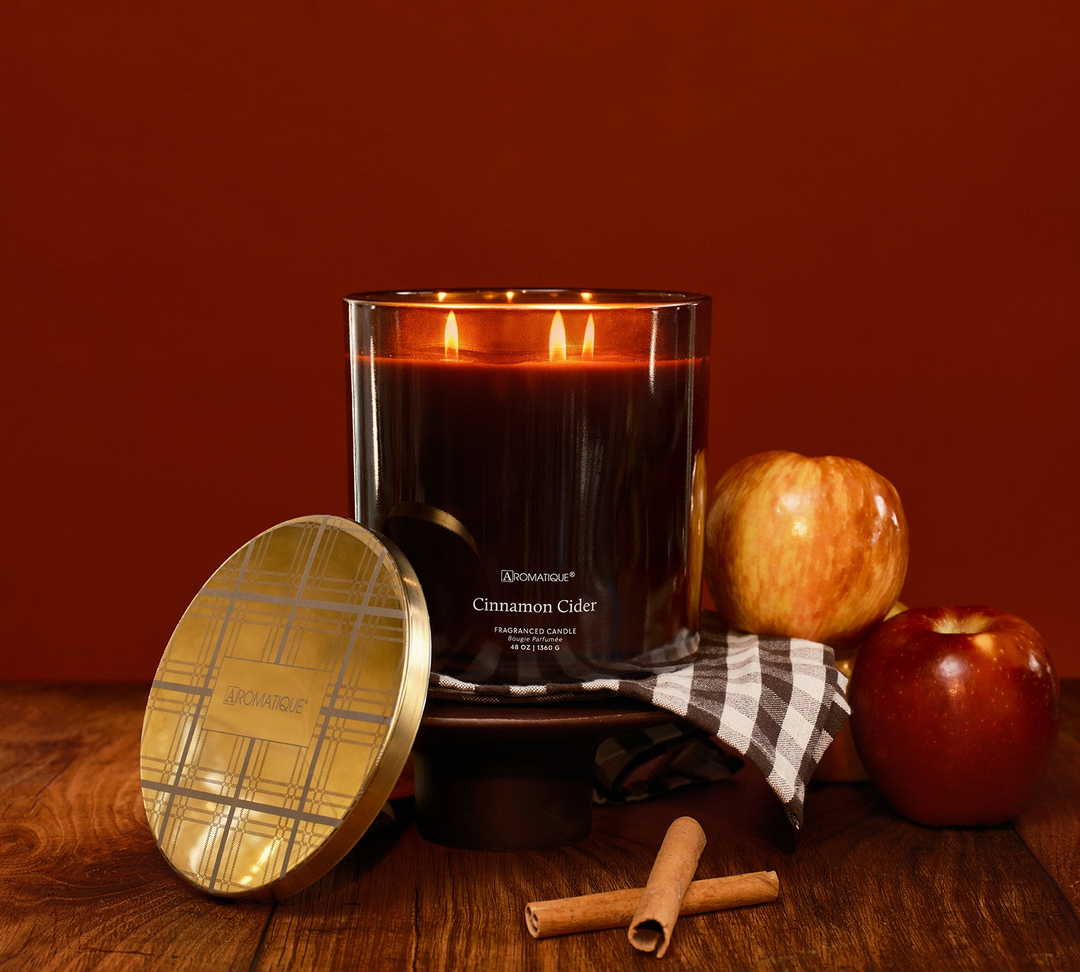 Cinnamon Cider 48 oz Statement Foundry Candle in amber glass with gold lid, apples, and cinnamon.