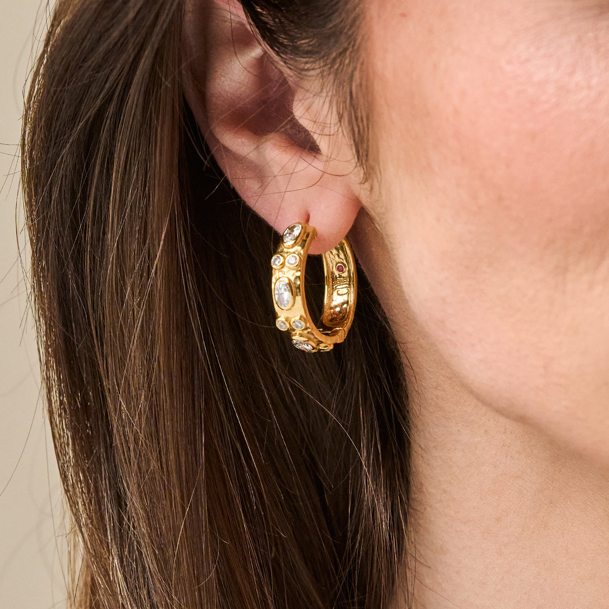 Maharani Huggie Hoop Earrings in gold with oval and round bezel-set clear cubic zirconia stones.