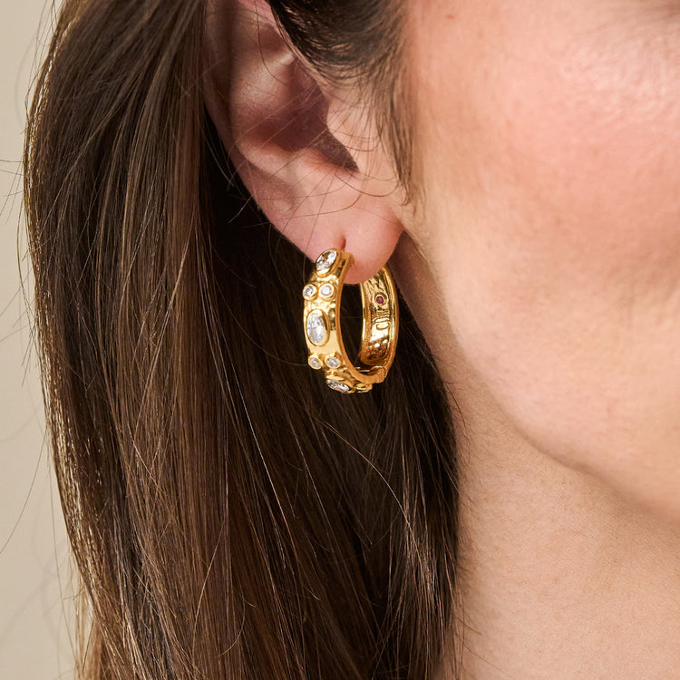 Maharani Huggie Hoop Earrings in gold with oval and round bezel-set clear cubic zirconia stones.
