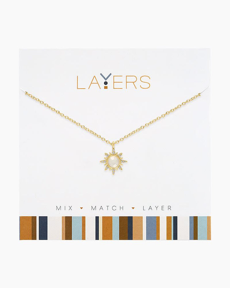 Gold Sunburst Layers Necklace featuring a sun-shaped pendant with a white stone on a gold chain.