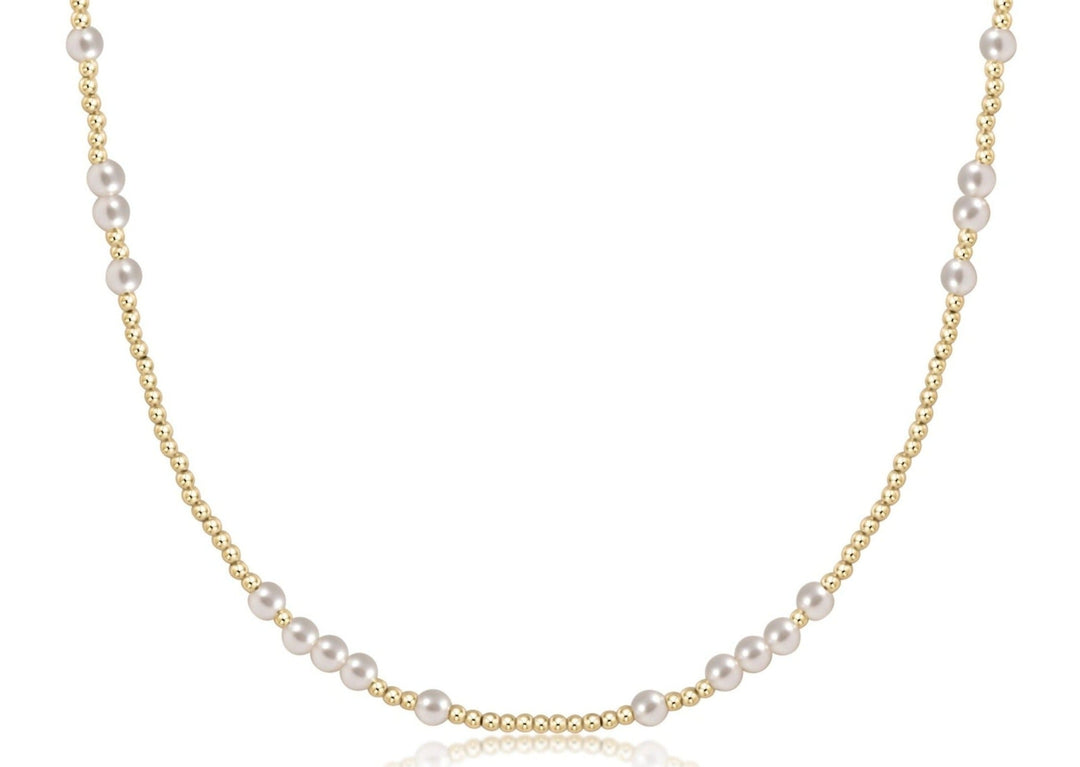 A close-up view of a choker necklace featuring four-millimeter white pearls and two-millimeter gold-filled beads.