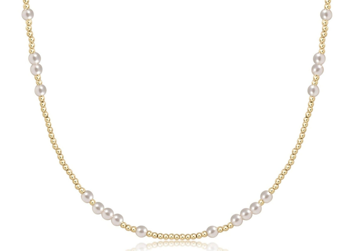 A close-up view of a choker necklace featuring four-millimeter white pearls and two-millimeter gold-filled beads.