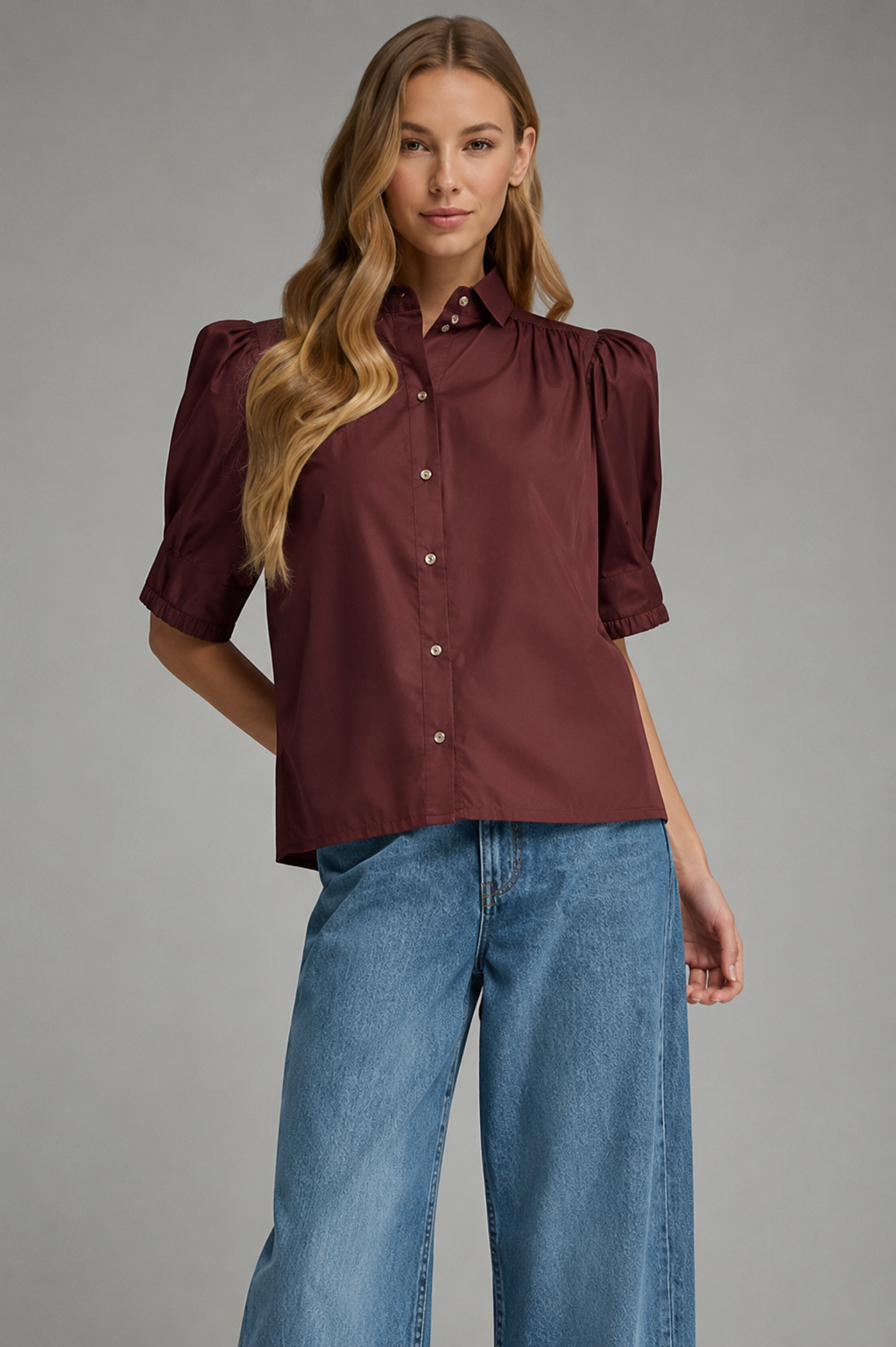 Woman wearing the Delia T32670 Top in burgundy with short puff sleeves and blue jeans.