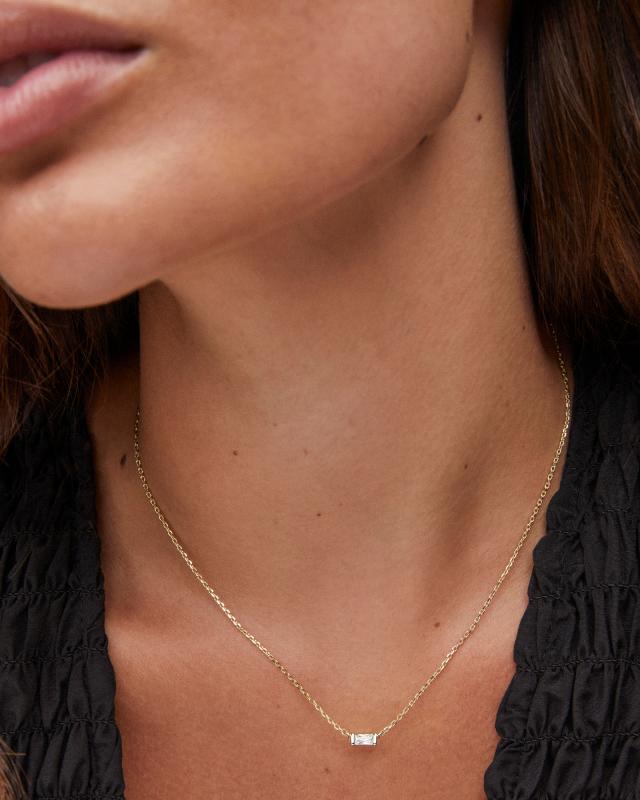 A person wearing the Juliette Pendant Necklace with a gold chain and a single baguette crystal.