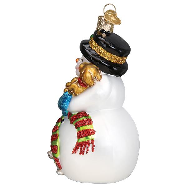 Side view of a glass snowman ornament wearing a black top hat and scarf, holding a golden puppy.