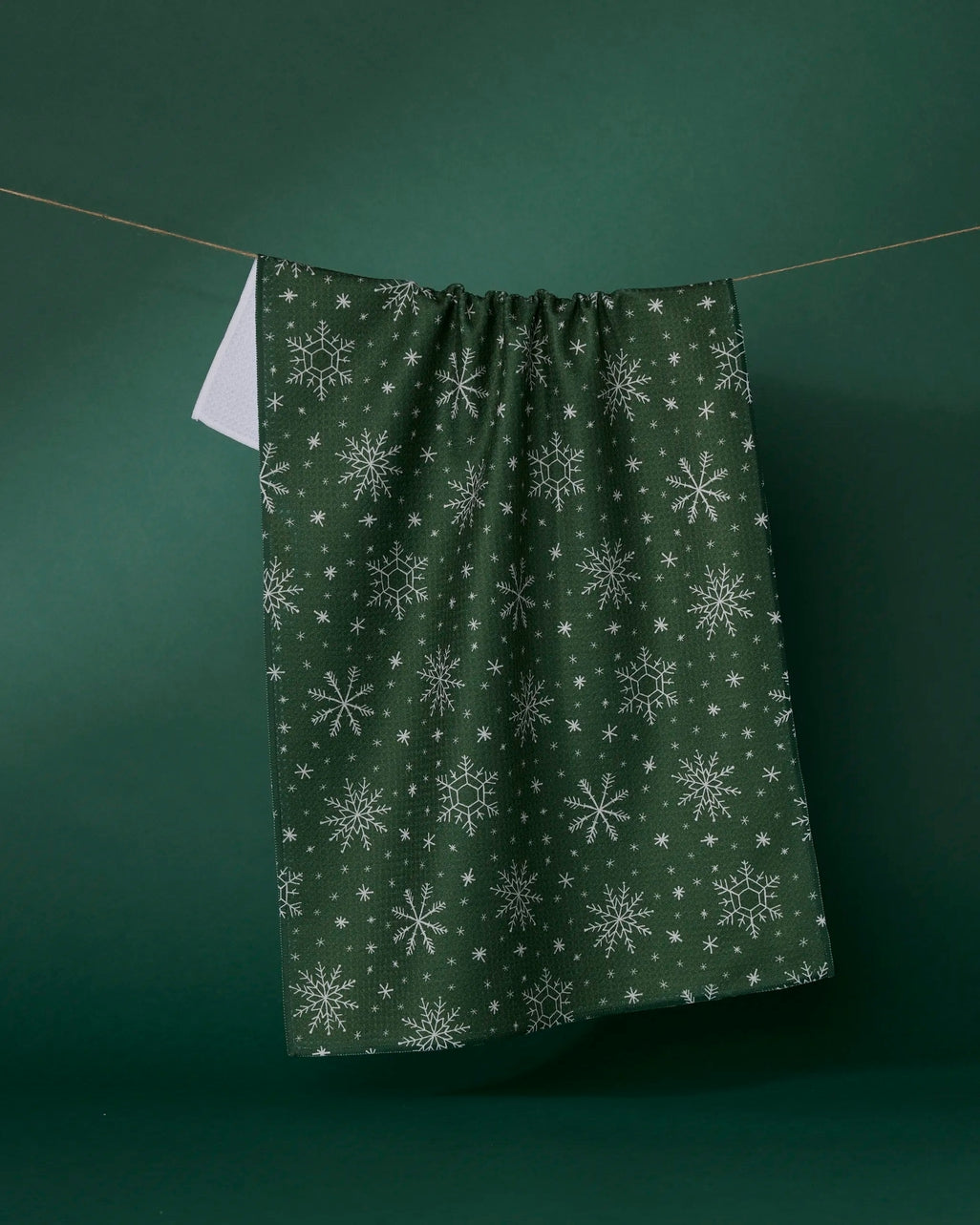 Holiday-themed waffle weave kitchen tea towel in red with white snowflake pattern.