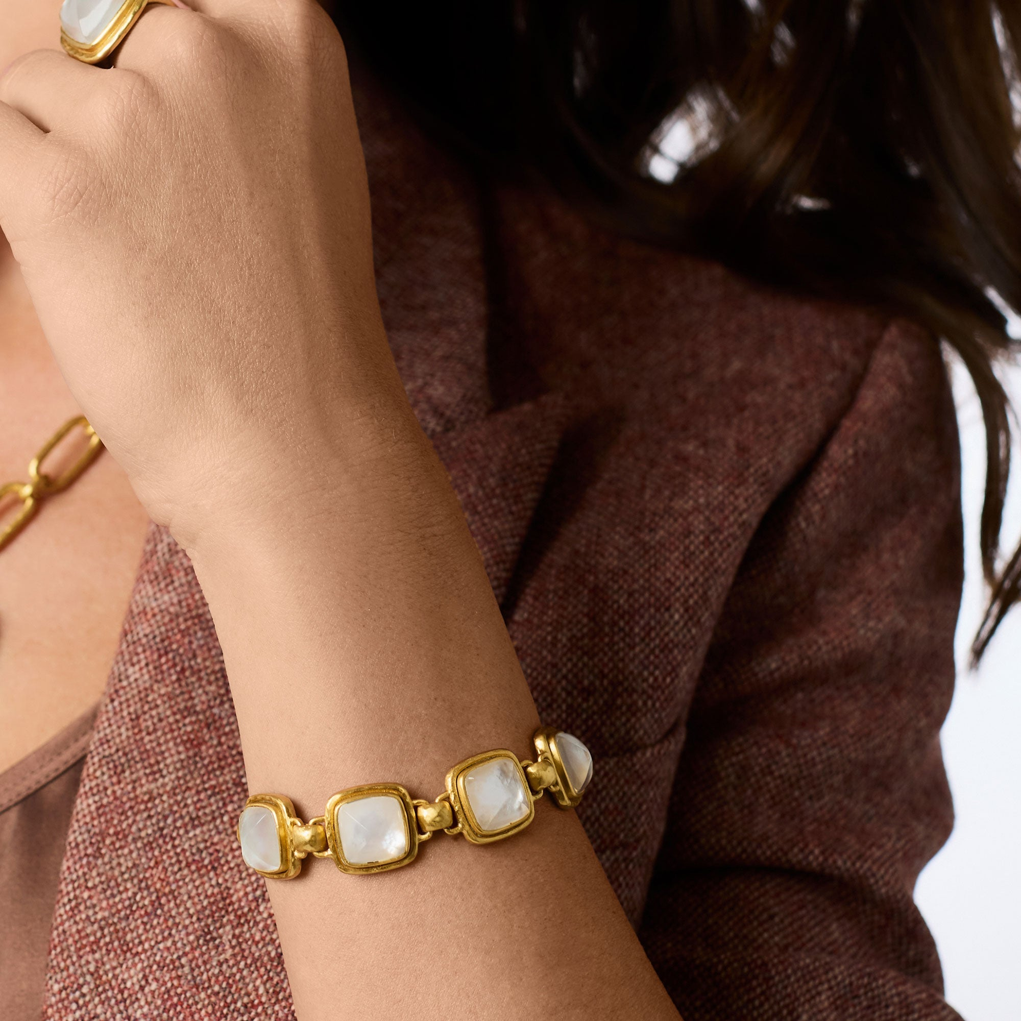 A person wearing the Sahara Stone Bracelet in 24K gold plate with square white glass stones.