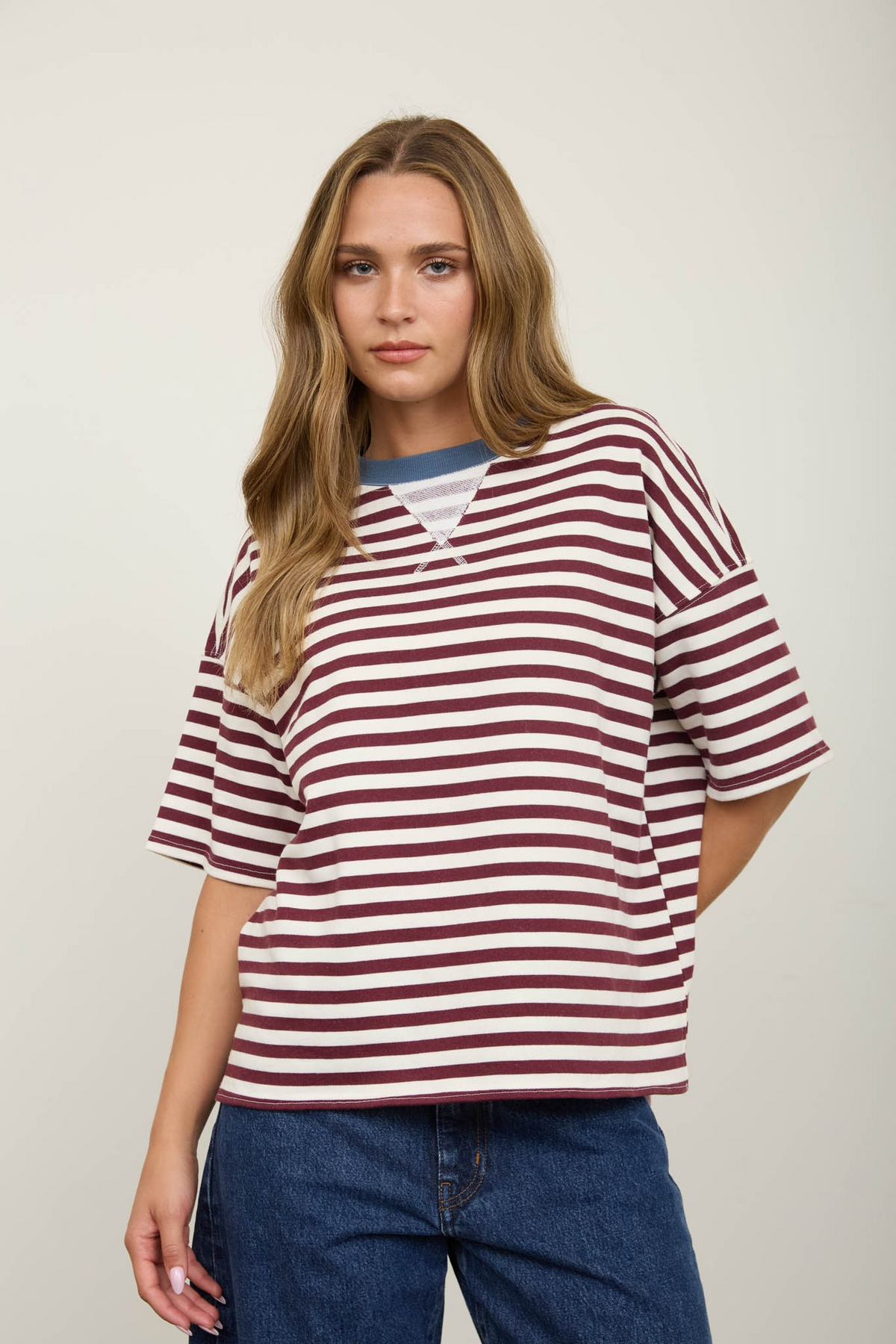 Woman wearing a burgundy and white striped short sleeve knit t-shirt with a blue contrast collar.