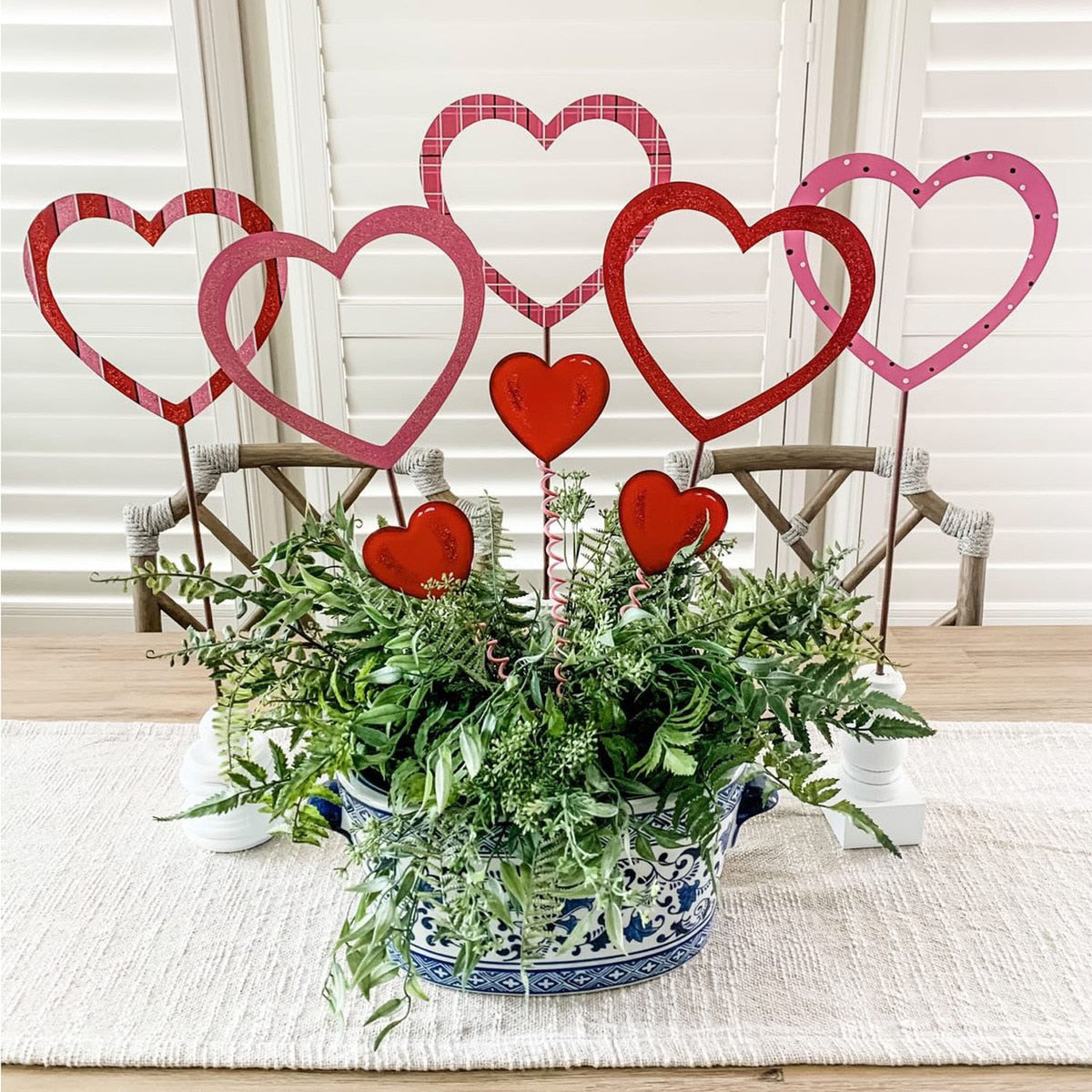 Three heart-shaped metal stakes with a matte finish designed as garden markers.