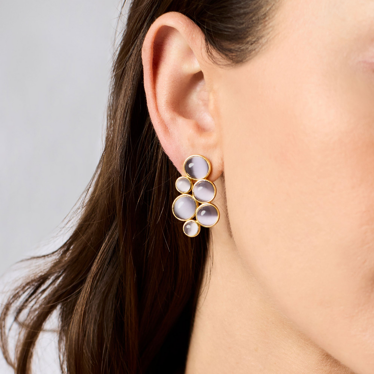 Model wearing Cobblestone Statement Earrings in 24K gold plate with grey glass cabochons.