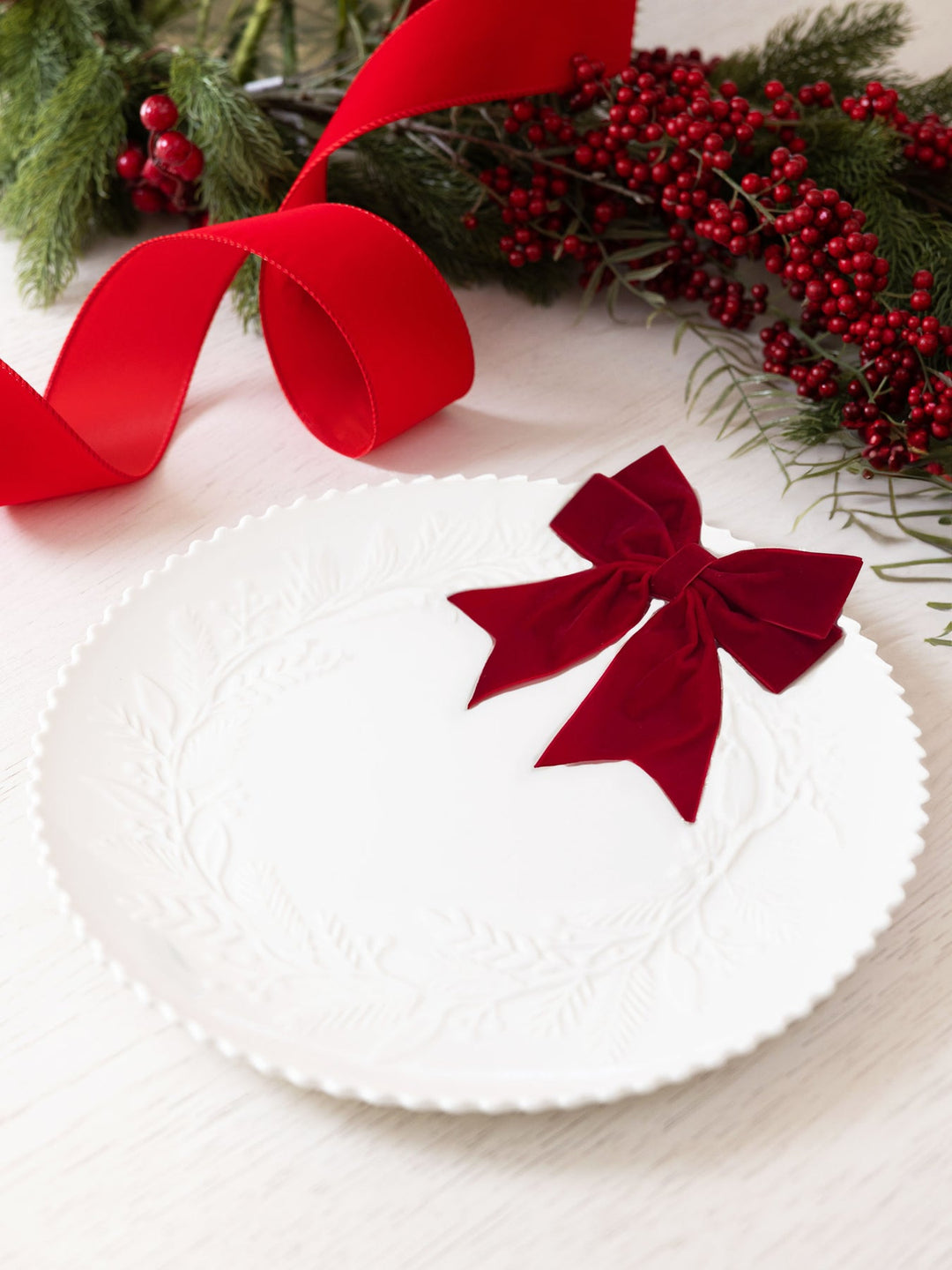 White 14-inch ceramic platter with an embossed wreath design, beaded edge, and a red velvet bow.