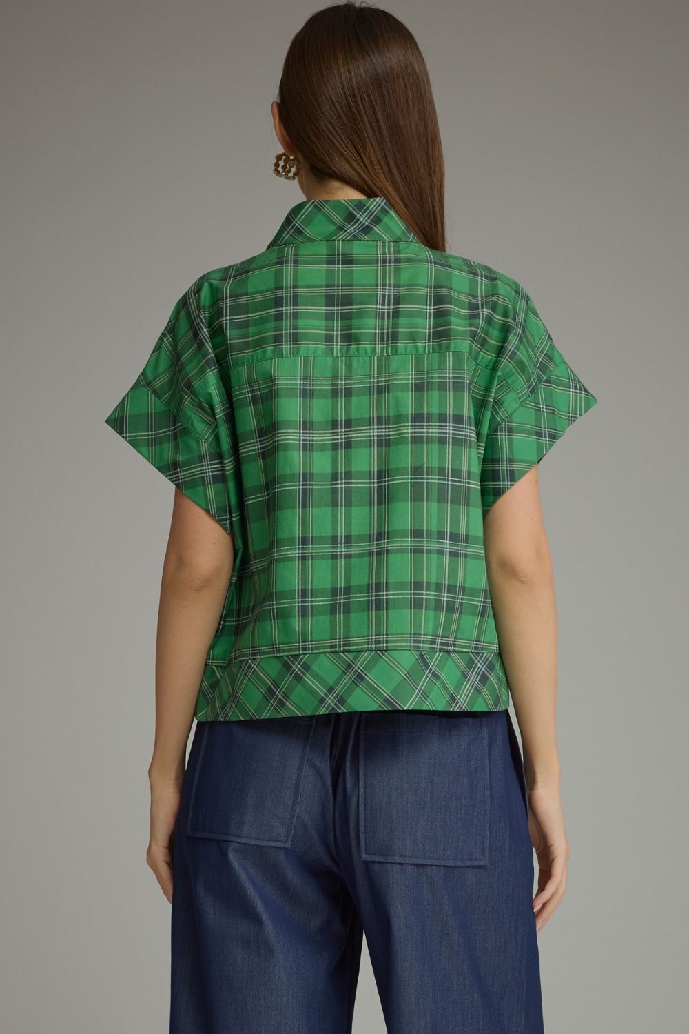 Back view of a woman wearing a green Chloe Plaid Short Sleeve Top and dark blue denim pants.