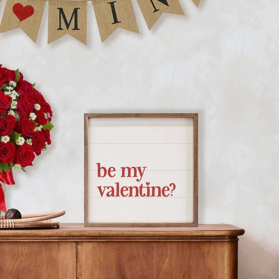 Square white wood sign with 'be my valentine?' in red text, framed in natural walnut.