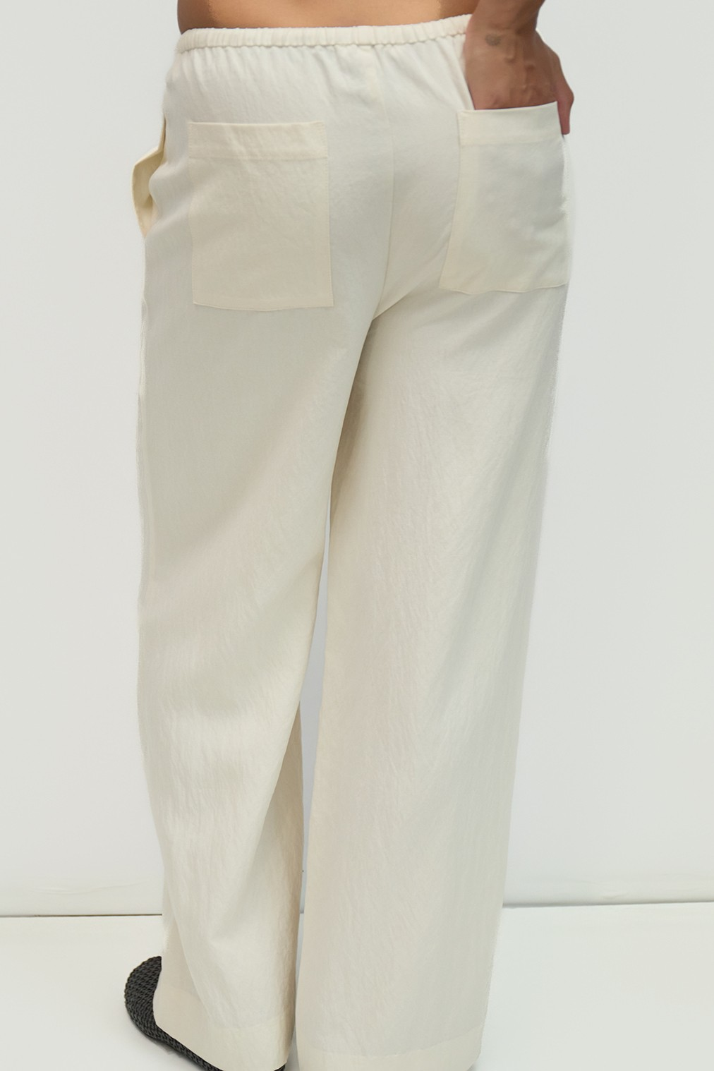 Rear view of a person wearing off-white, wide-leg Jodi Pants with back patch pockets.