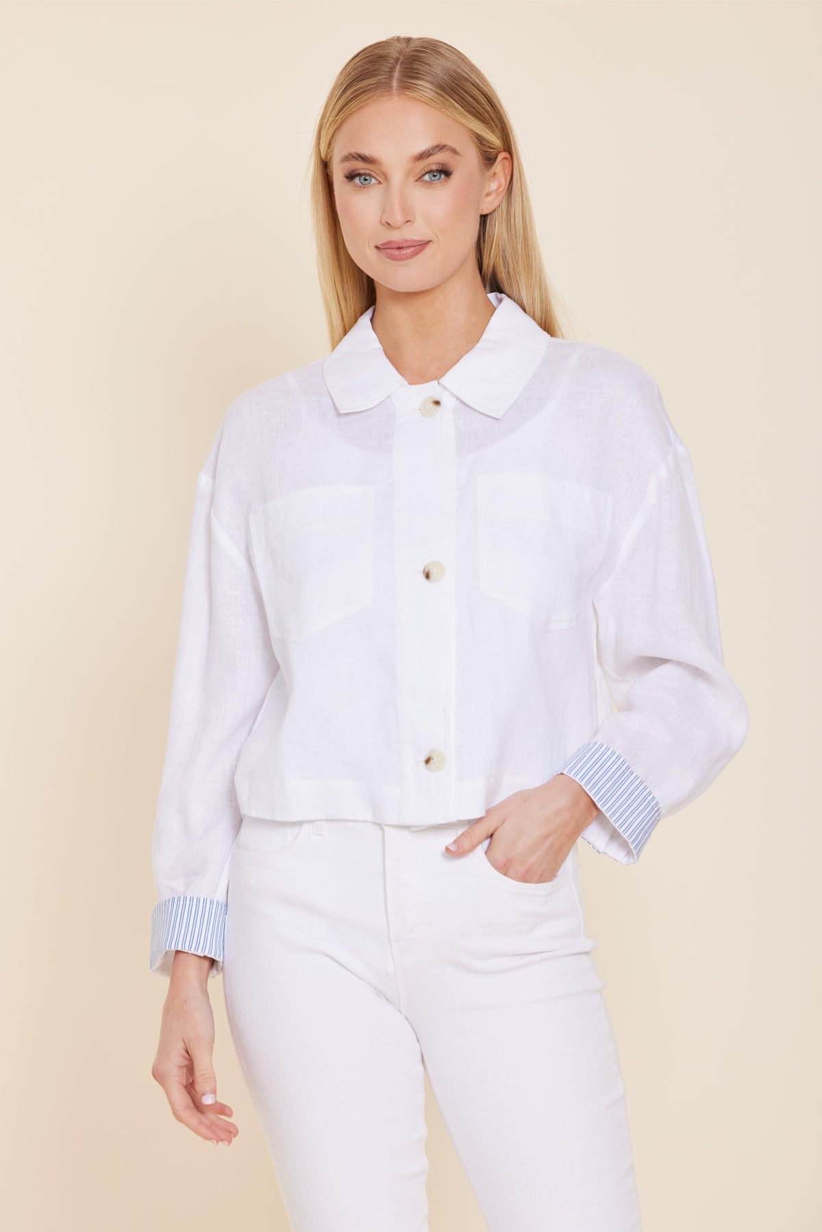 Woman wearing a white Grace Linen Jacket with button-up front and blue pin stripe cuffs.
