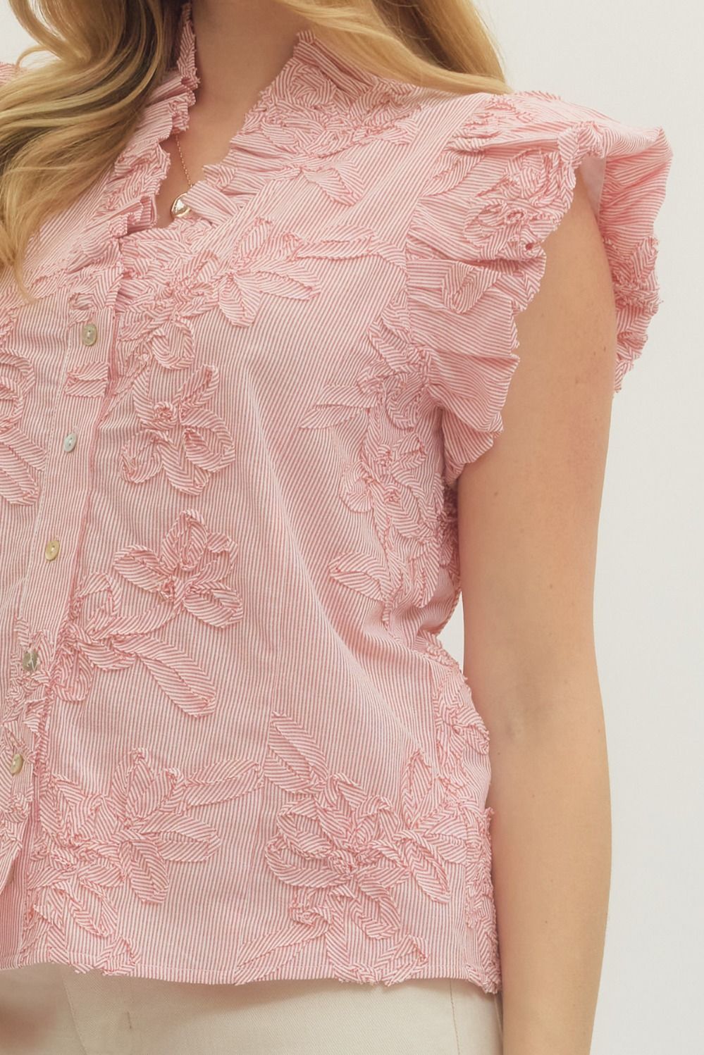 Leslie striped cotton top with floral appliqué, ruffled mock neck, flutter sleeves, and button front closure in light colors.