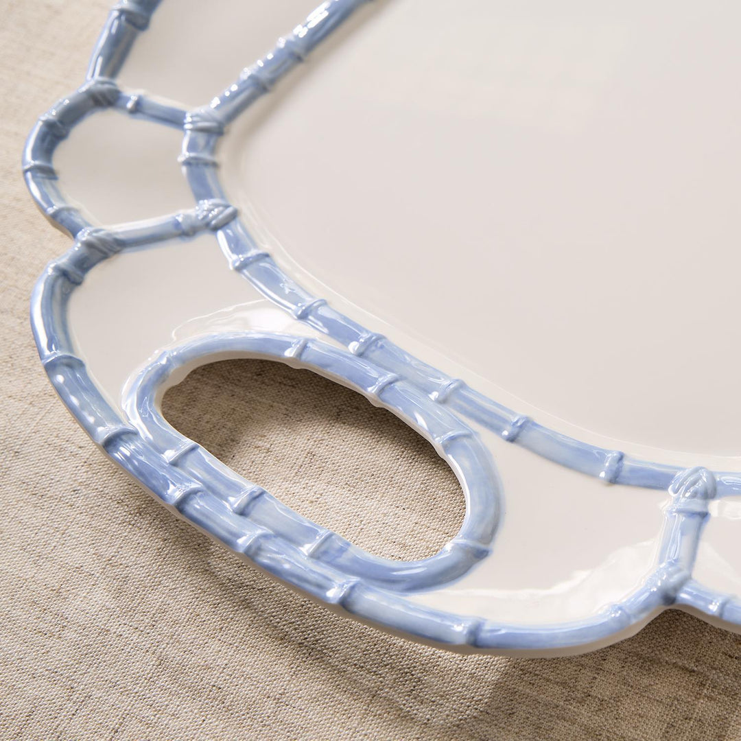Close-up of a white melamine platter with a light blue bamboo-style rim and handle cutout.