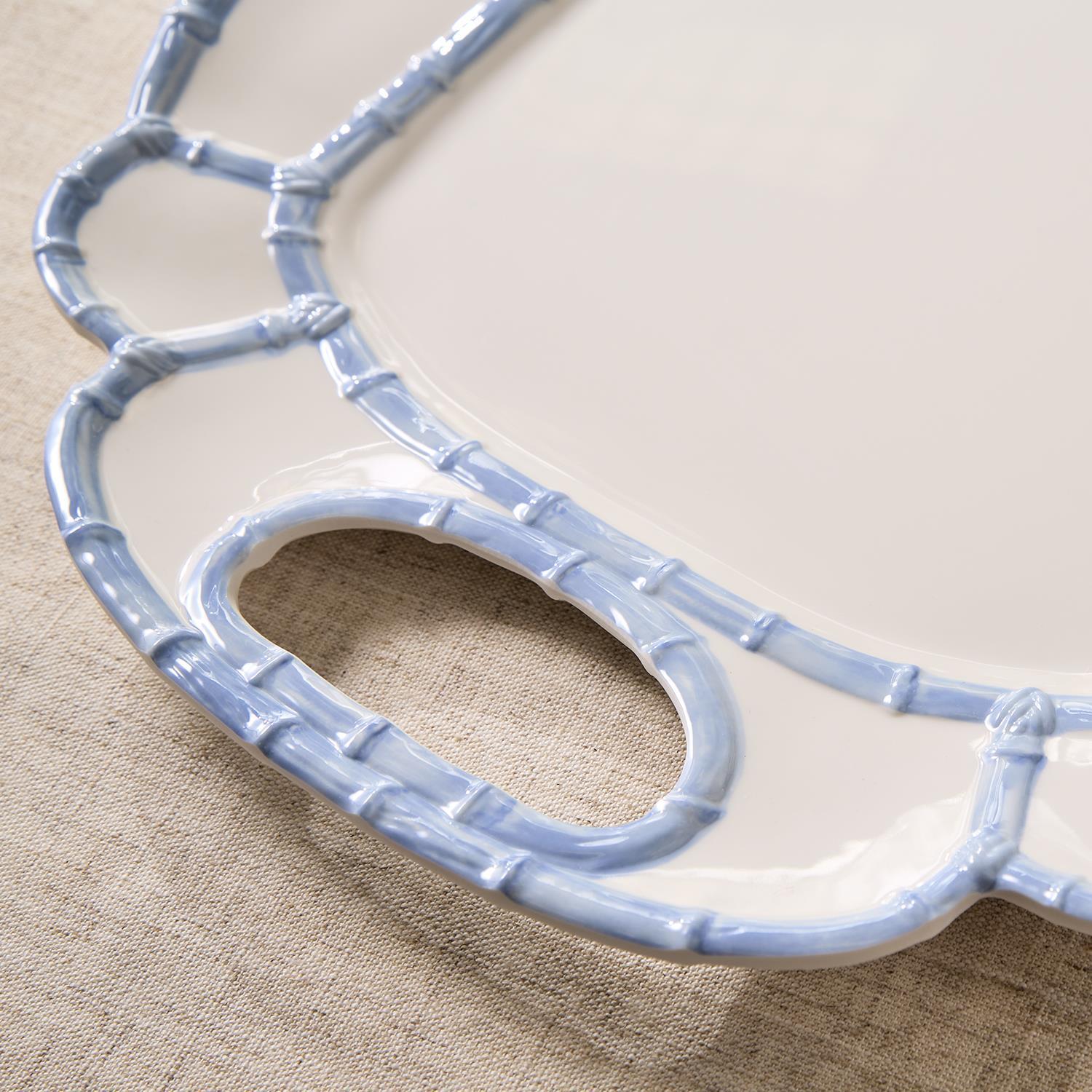 Close-up of a white melamine platter with a light blue bamboo-style rim and handle cutout.