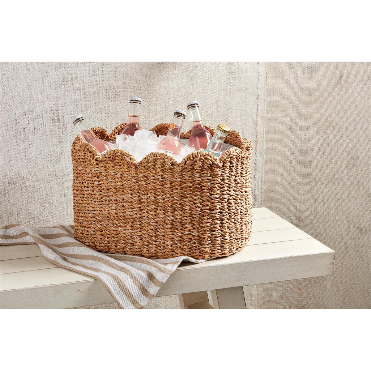 Woven seagrass party tub with a scalloped rim, filled with ice and bottled drinks on a white bench.