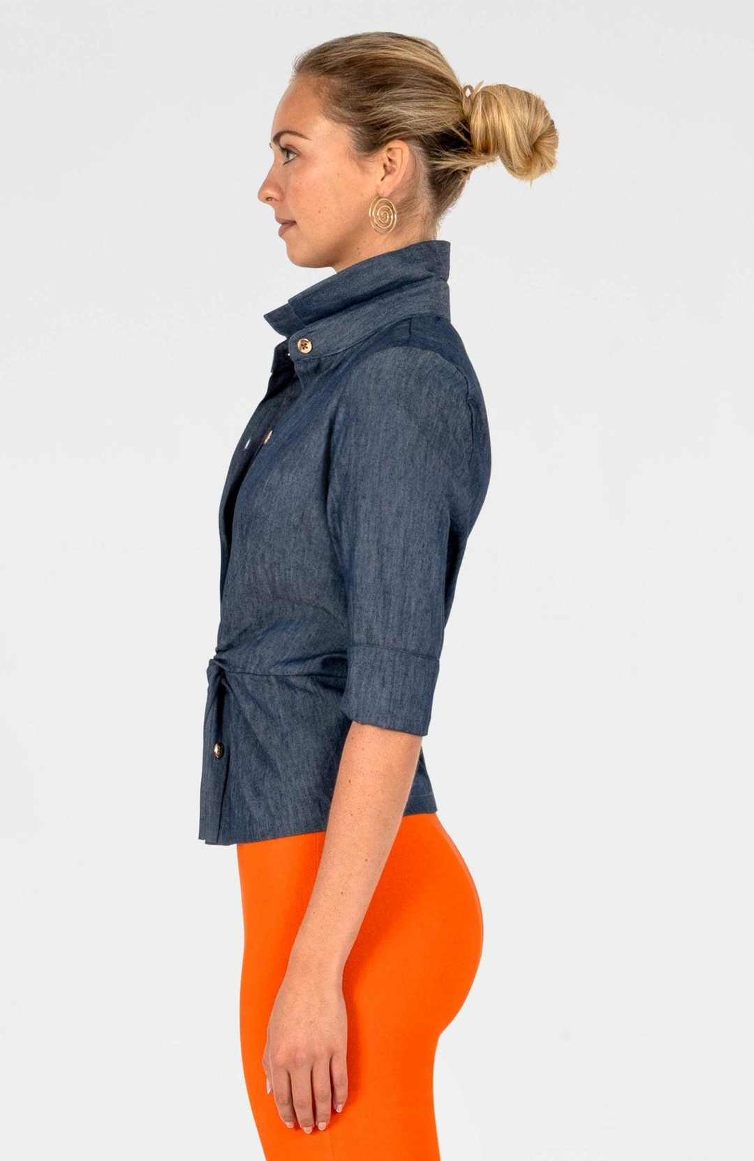 Side view of a woman wearing the Wendy Twist & Shout Top in dark denim with orange pants.