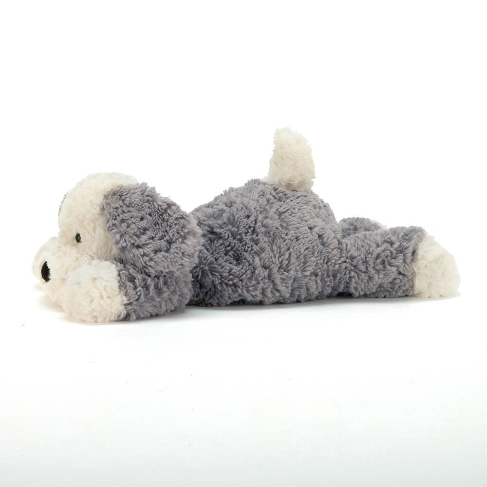 A plush Tumblie Sheep Dog in grey and white fur, lying flat on its belly.