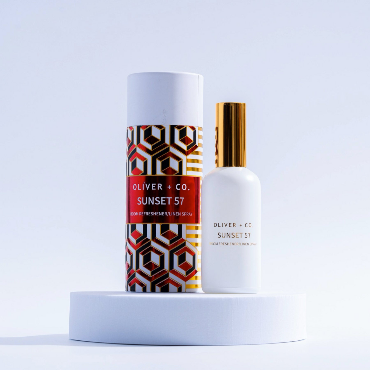 Oliver + Co. Sunset 57 Room Refresher and Linen Spray bottle next to its geometric patterned tube.