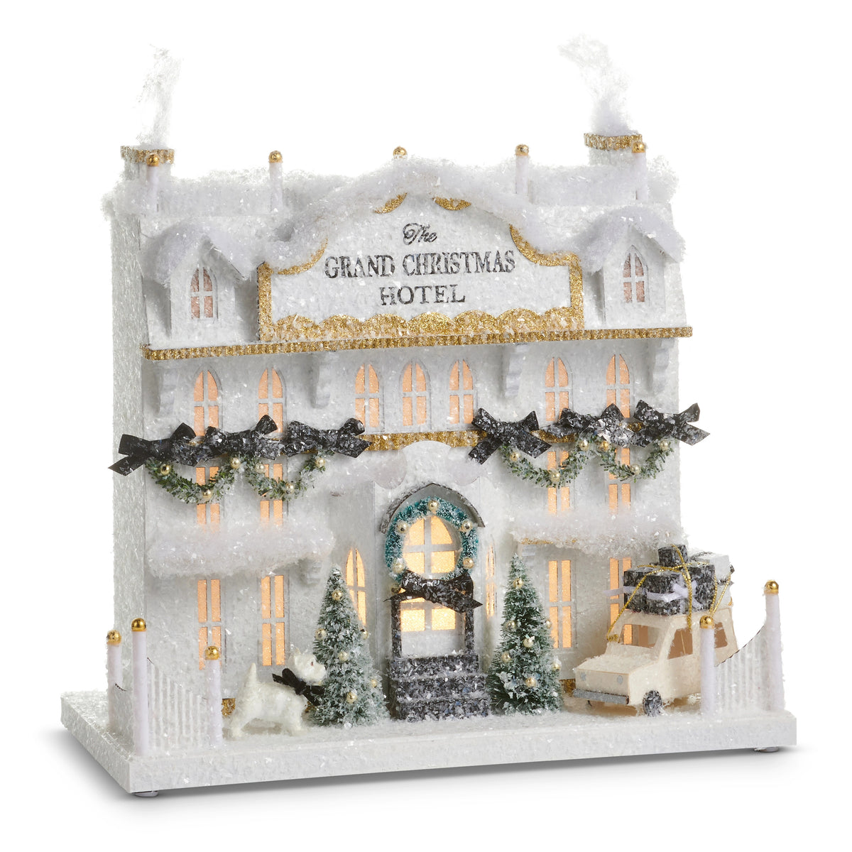 14.5 inch lighted paper Grand Christmas Hotel with snow, trees, a dog, and a car with gifts.