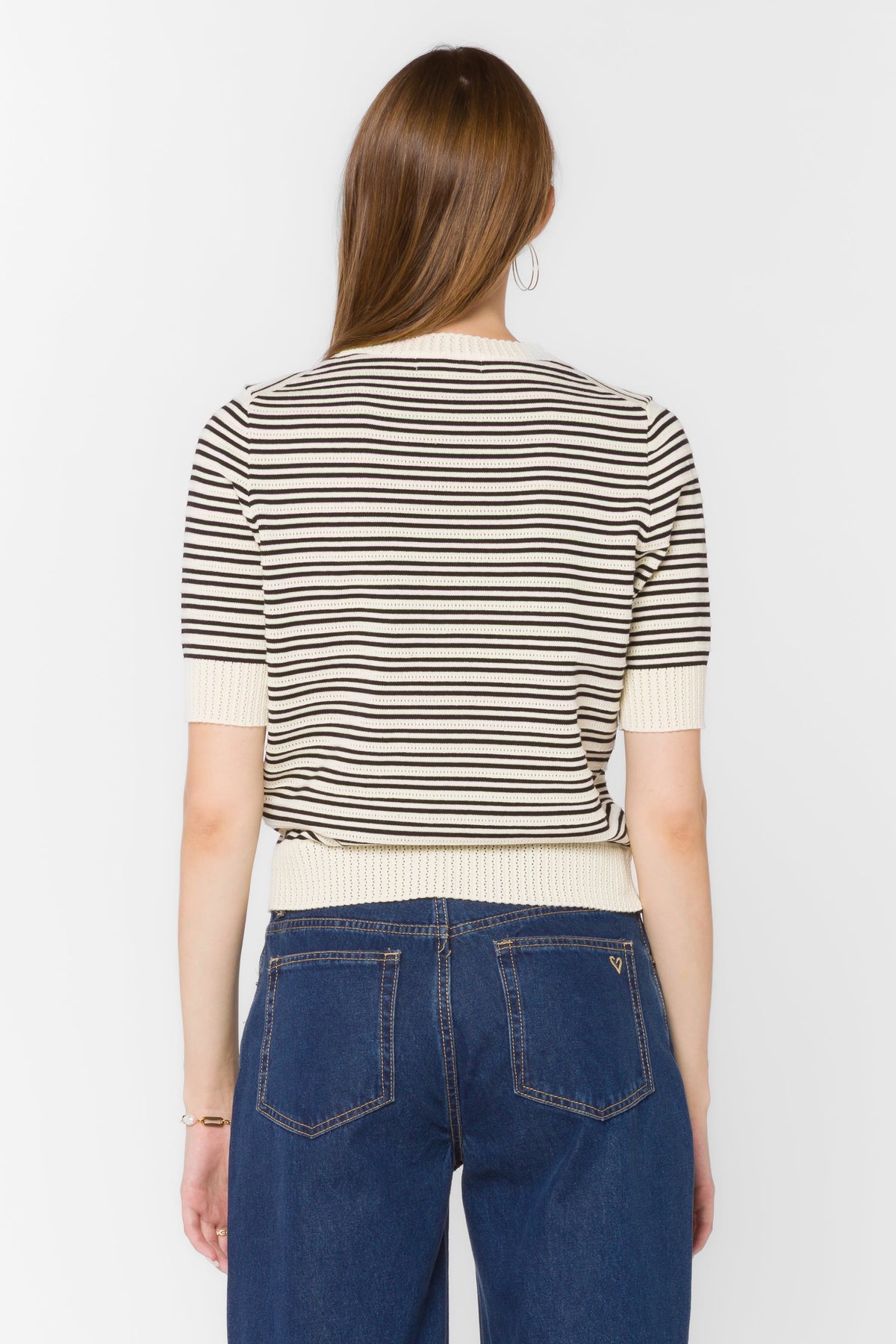 Woman wearing a white short-sleeve cotton sweater with ribbed crew neckline, sleeves, and hem.