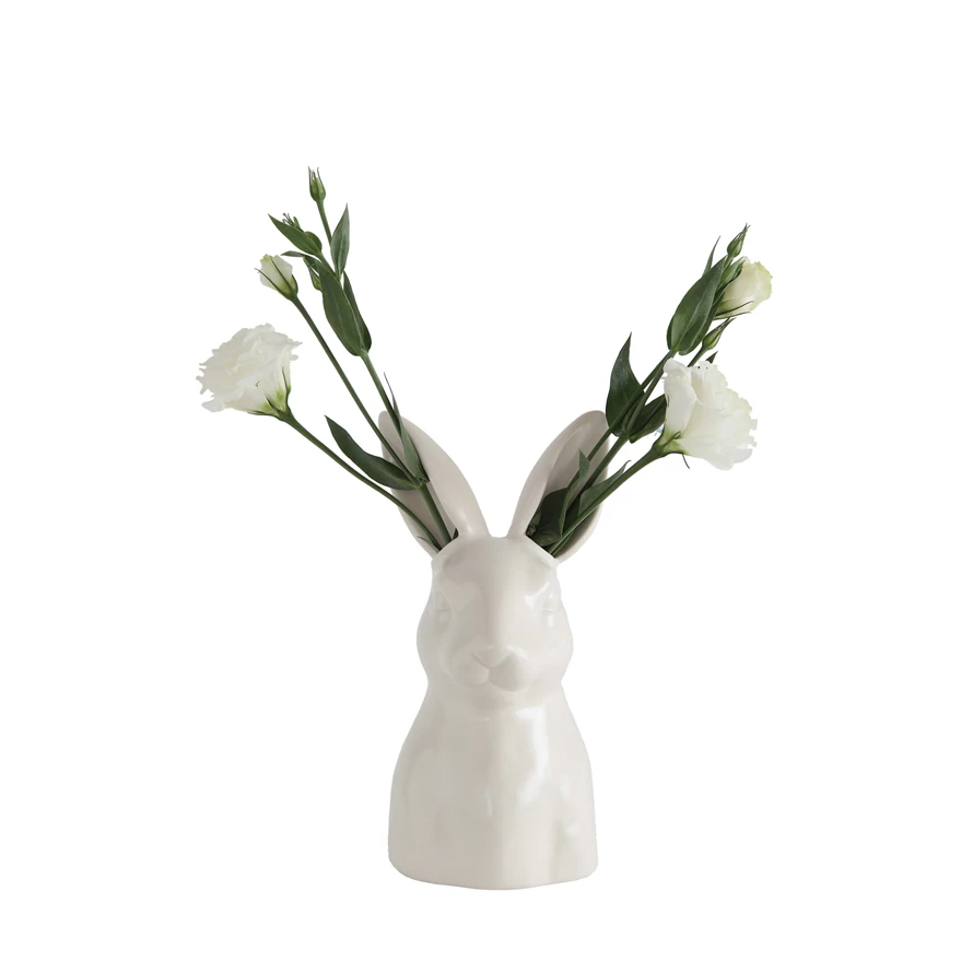 White ceramic bunny vase holding white flowers and green stems. Watertight.