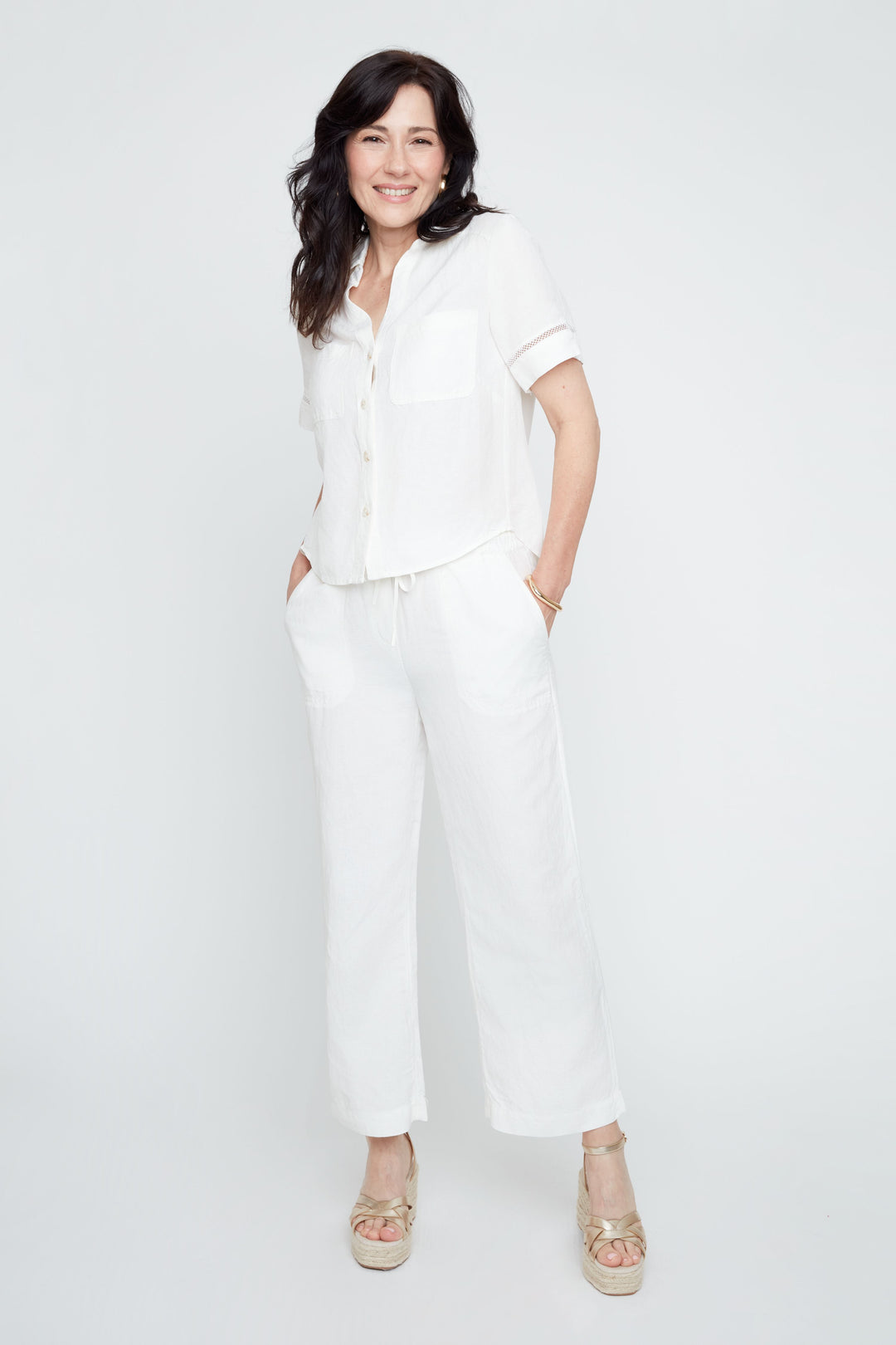 Woman in a white linen short-sleeve button-up blouse and matching wide-leg pants.