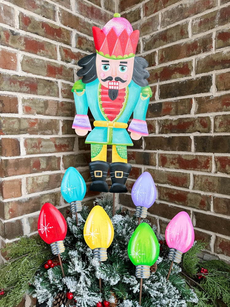 Merry & Bright medium nutcracker stake with red coat, black hat, and white beard standing upright.