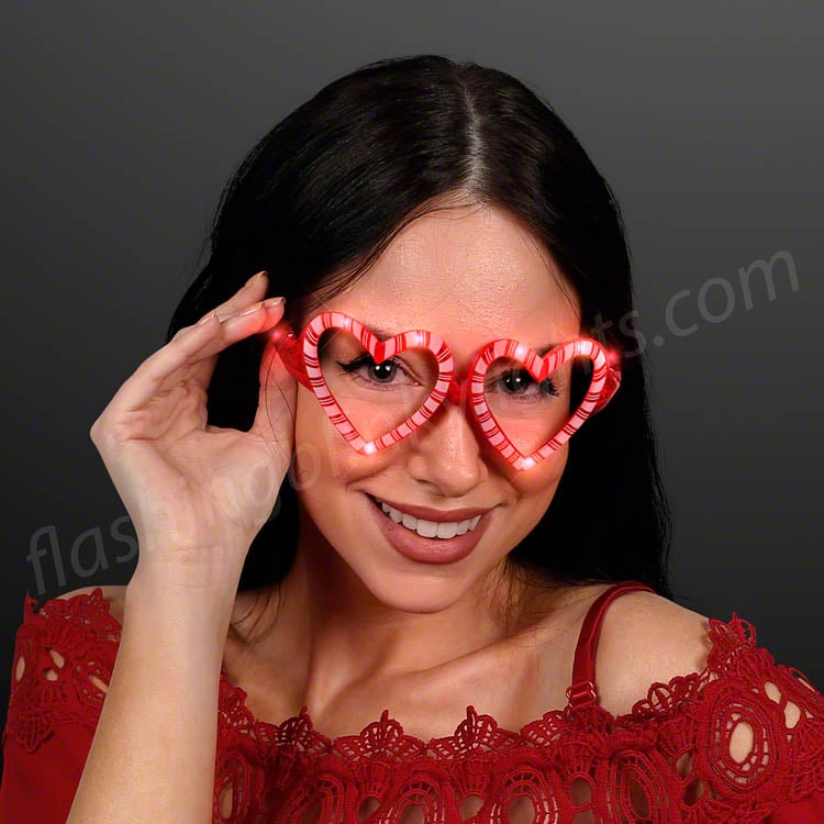 Woman wearing Holiday Hearts Light Up Candy Cane Glasses with red and white striped heart frames.
