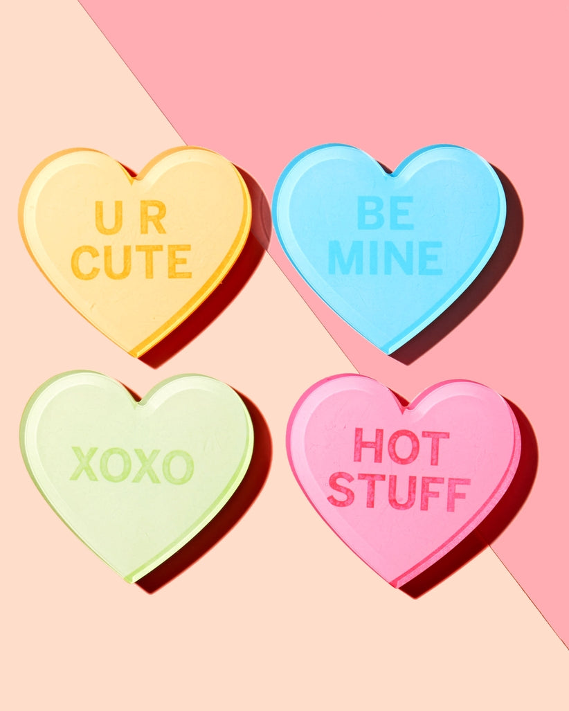Four acrylic coasters featuring red hearts on a white background with black text.