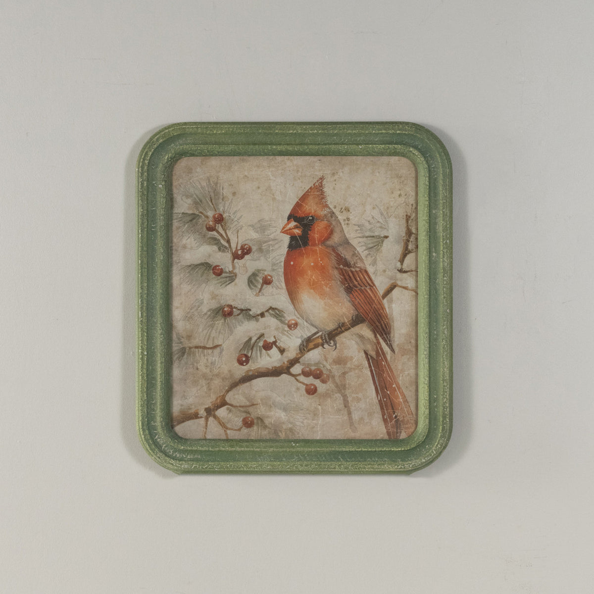 Framed winter scene print on glass showing a red cardinal perched in snow-covered branches against a blue sky.