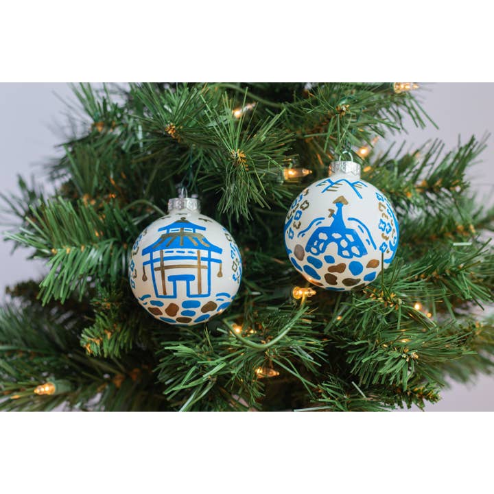 Hand-painted ceramic ornament featuring a pagoda scene with red roof tiles against a white background.