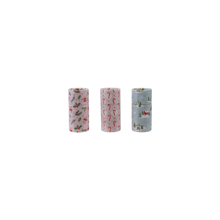 Three small tube matchboxes with holiday patterns: holly on pink, candy canes, and a winter scene.