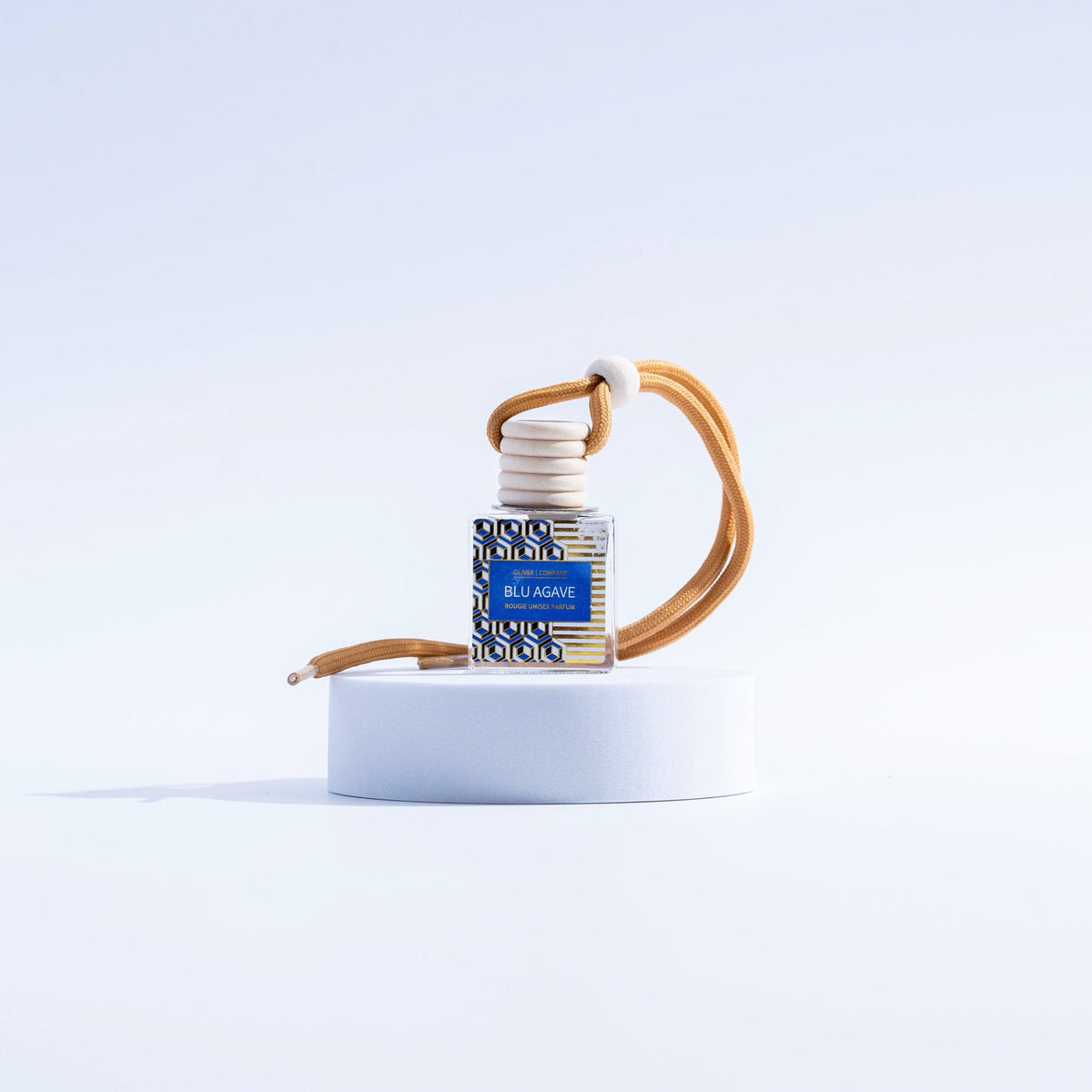 Blue Agave Bougie On-The-Go Car Freshener with a wooden cap and tan hanging cord on a white pedestal