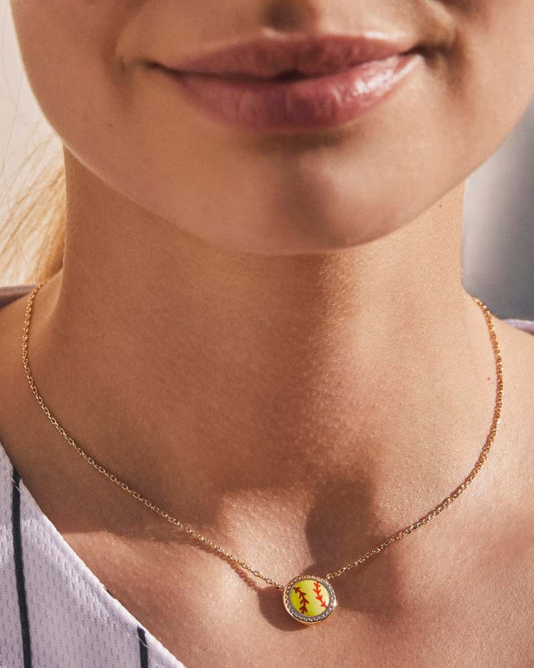 Woman wearing a gold necklace with a chartreuse magnesite softball-shaped pendant.