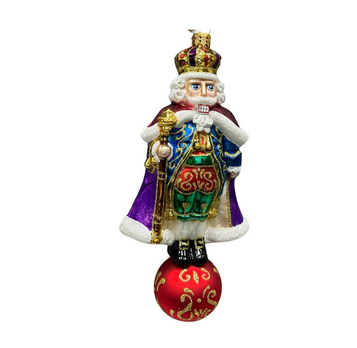 The Noble Nutcracker glass ornament with a purple cape, gold staff, and red ball base.