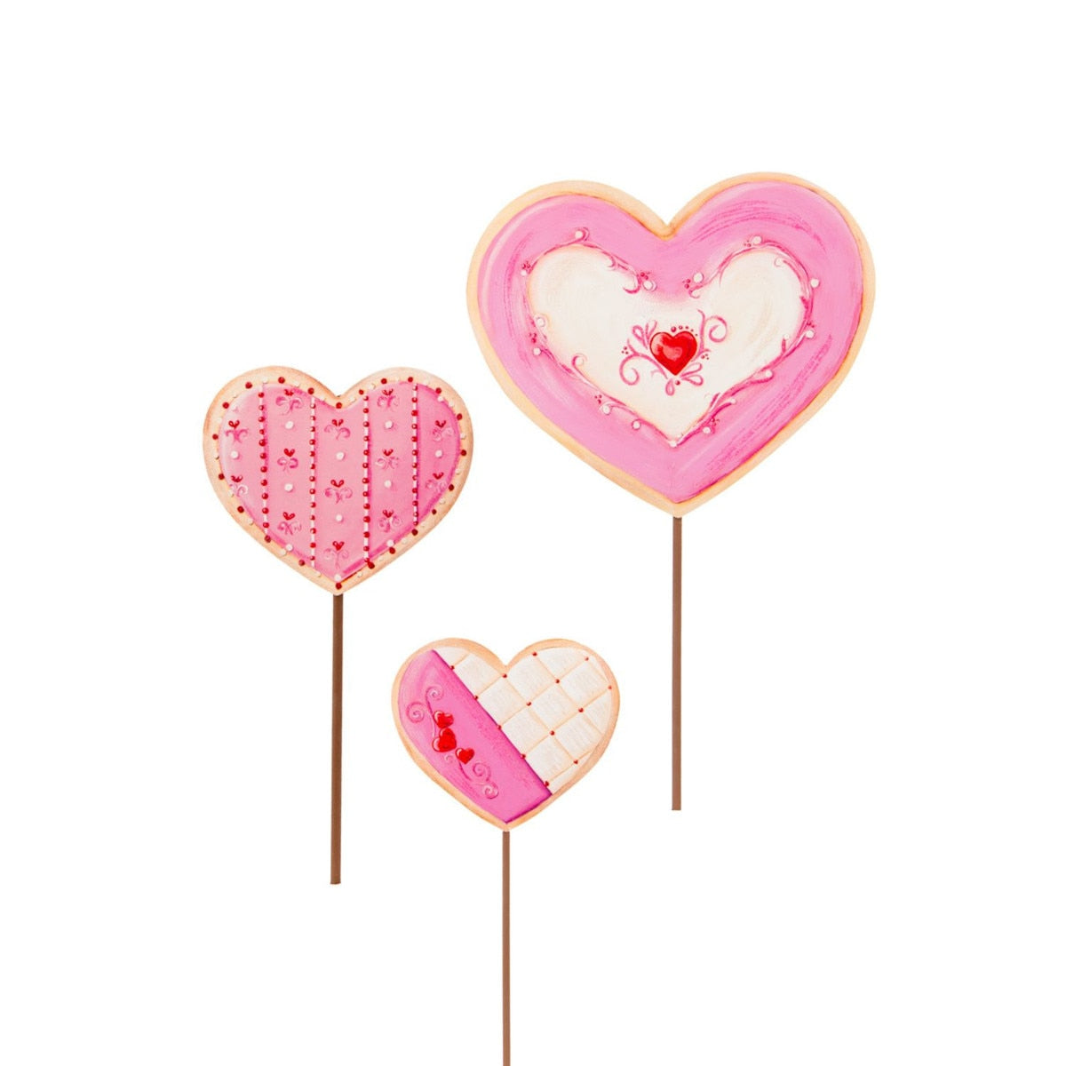Three heart-shaped cookie decorations on sticks, in pink and white with decorative patterns and small red hearts.