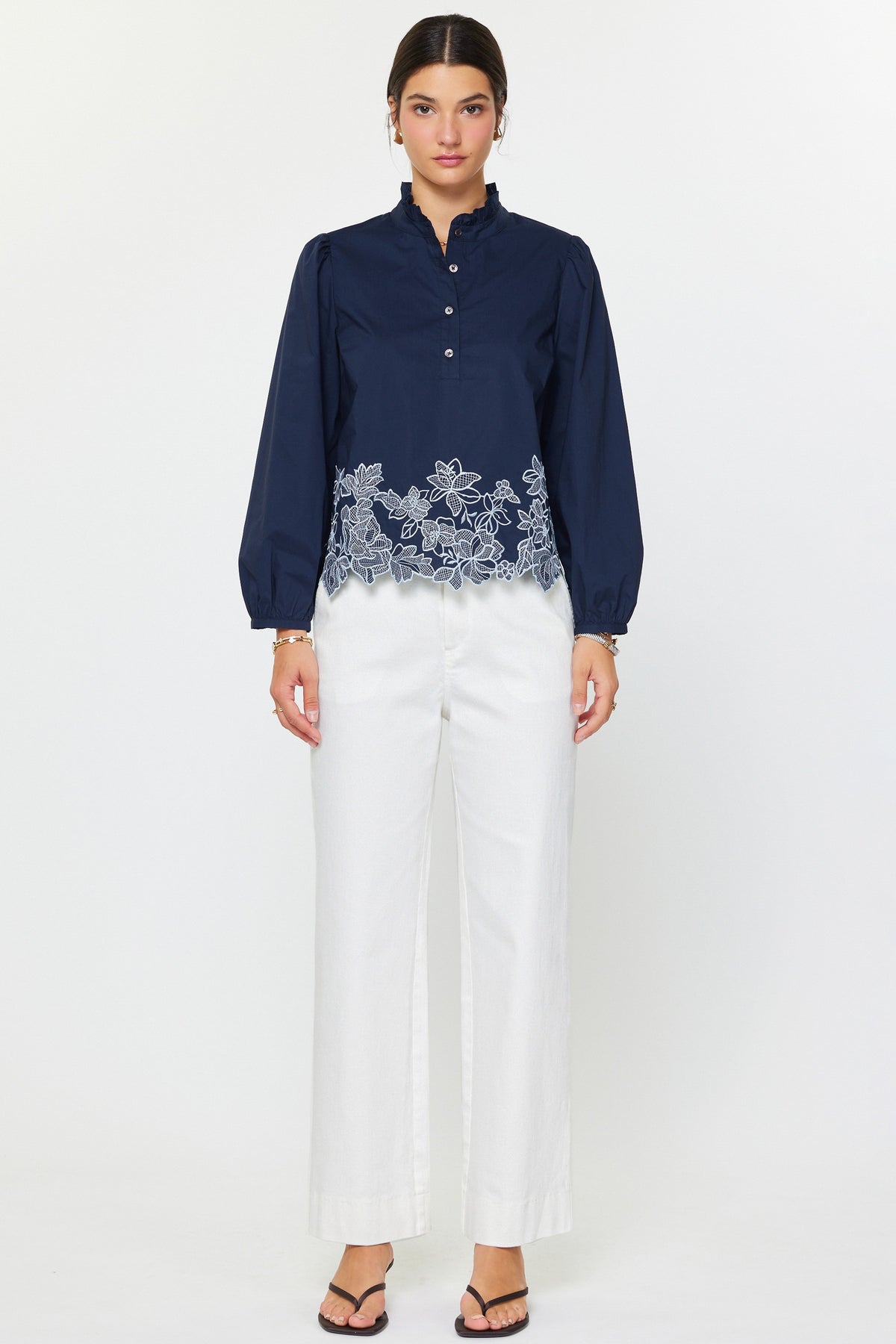 Lucy embroidered long sleeve blouse in cotton poplin with ruffle stand collar, puff sleeves, floral hem embroidery, and relaxed fit.