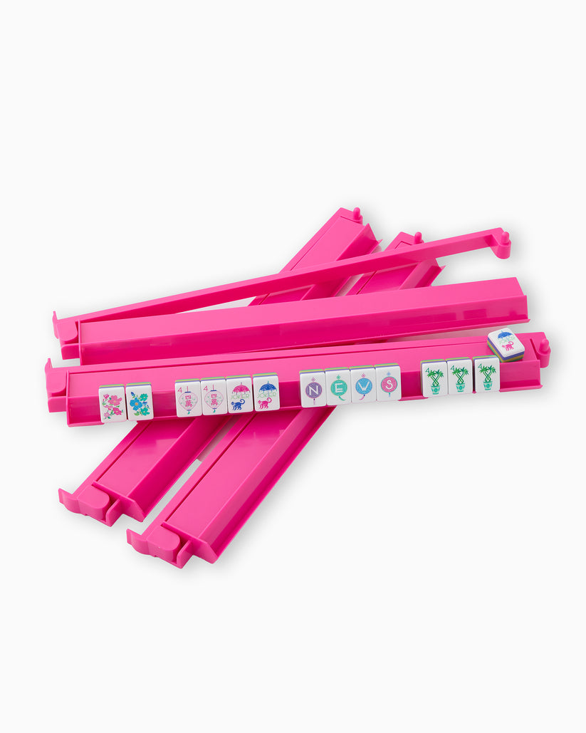Set of four hot pink acrylic mahjong racks and pushers with a few tiles displayed on one rack.