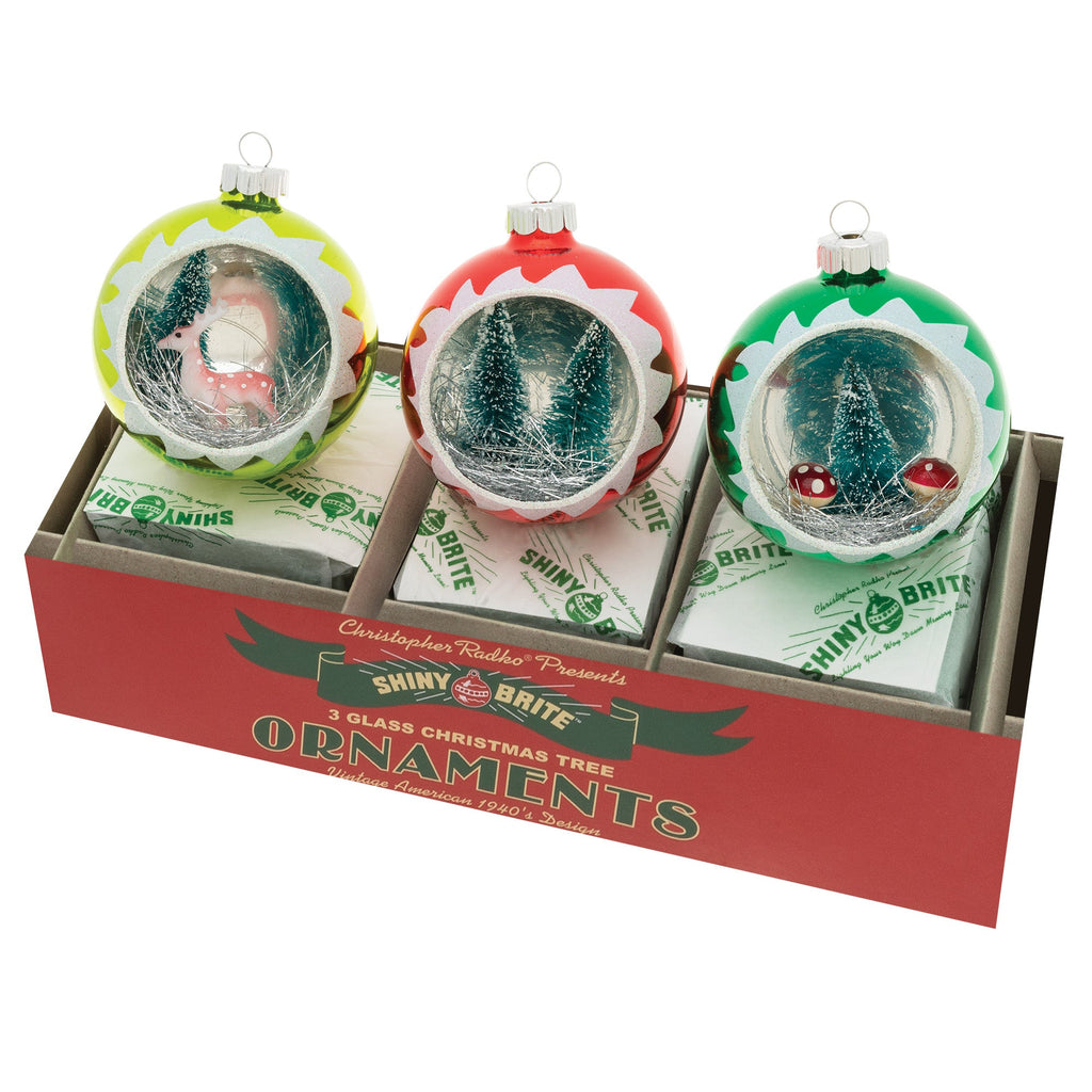 Three round ornaments with a shiny gold finish featuring red holly leaves and white snowflakes on a vintage-style box.